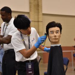 A SkillsUSA participant from ChattState cuts a mannequin's hair at the statewide SkillsUSA competition at the Chattanooga Convention Center in April 2024.
