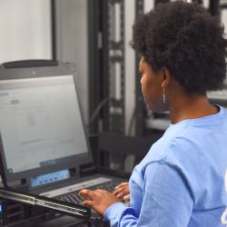 A woman in a blue shirt types on a computer.