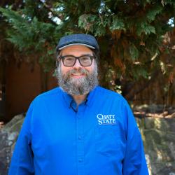 A bearded man in a wool hat smiles.