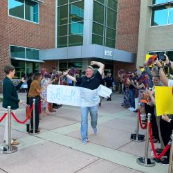 A SkillsUSA competitor from ChattState runs through a banner before boarding a bus to SkillsUSA nationals in Atlanta.