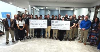 A group of well-dressed students, faculty, and business leaders hold two oversized checks from TVA and Westinghouse.
