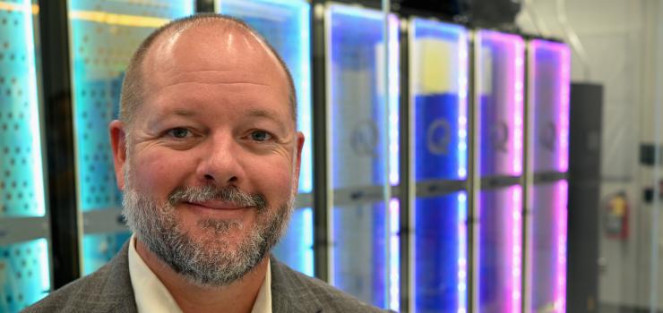 A man stands in front of colorful electronic panels.